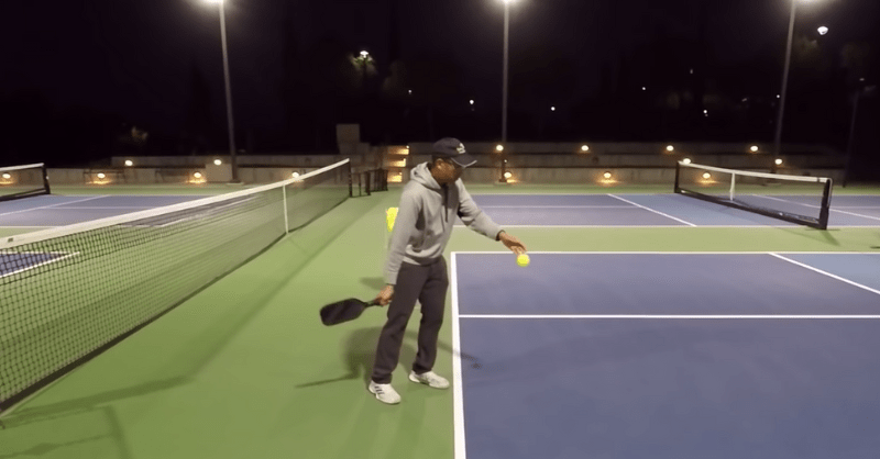 A player serving ball in a pickleball court